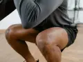 Mann in Sportkleidung macht Kniebeugen. Bei Schmerzen in der Kniekehle welcher Arzt ist der richtige Ansprechpartner?