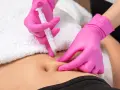 Hände in pinken Handschuhen spritzen unter die Haut. Eine Spritze wird präzise angesetzt, um eine Behandlung durchzuführen.