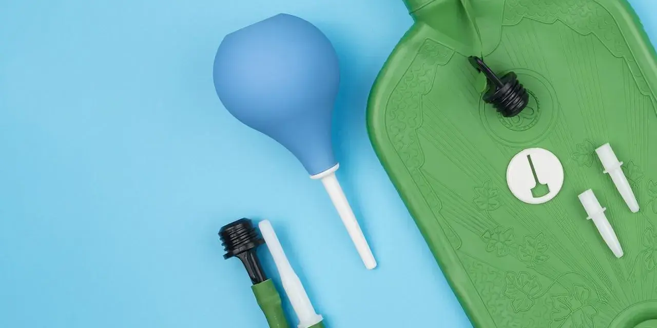 Grüne Wärmflasche mit Zubehör für einen hebe schwenkeinlauf. Blaue Birne und grüne Schläuche mit Aufsätzen liegen daneben.
