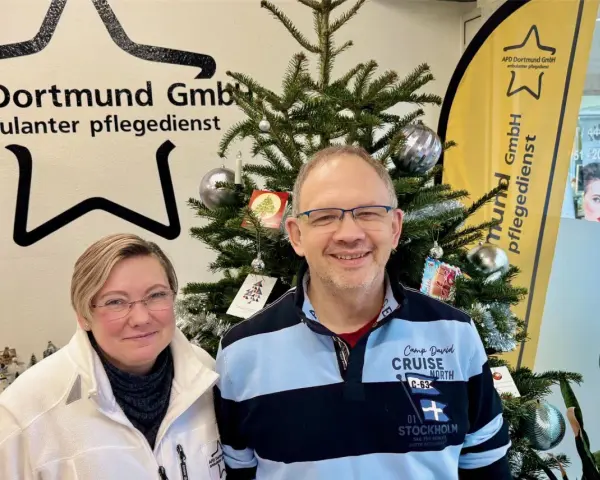 Zwei Mitarbeiter des ambulanten Pflegedienstes APD Dortmund stehen vor einem Weihnachtsbaum. Bei Fragen zum pflegedienst beschwerdestelle nrw sind sie gerne für Sie da.