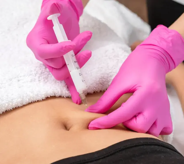 Hände in pinken Handschuhen spritzen unter die Haut. Eine Spritze wird präzise angesetzt, um eine Behandlung durchzuführen.