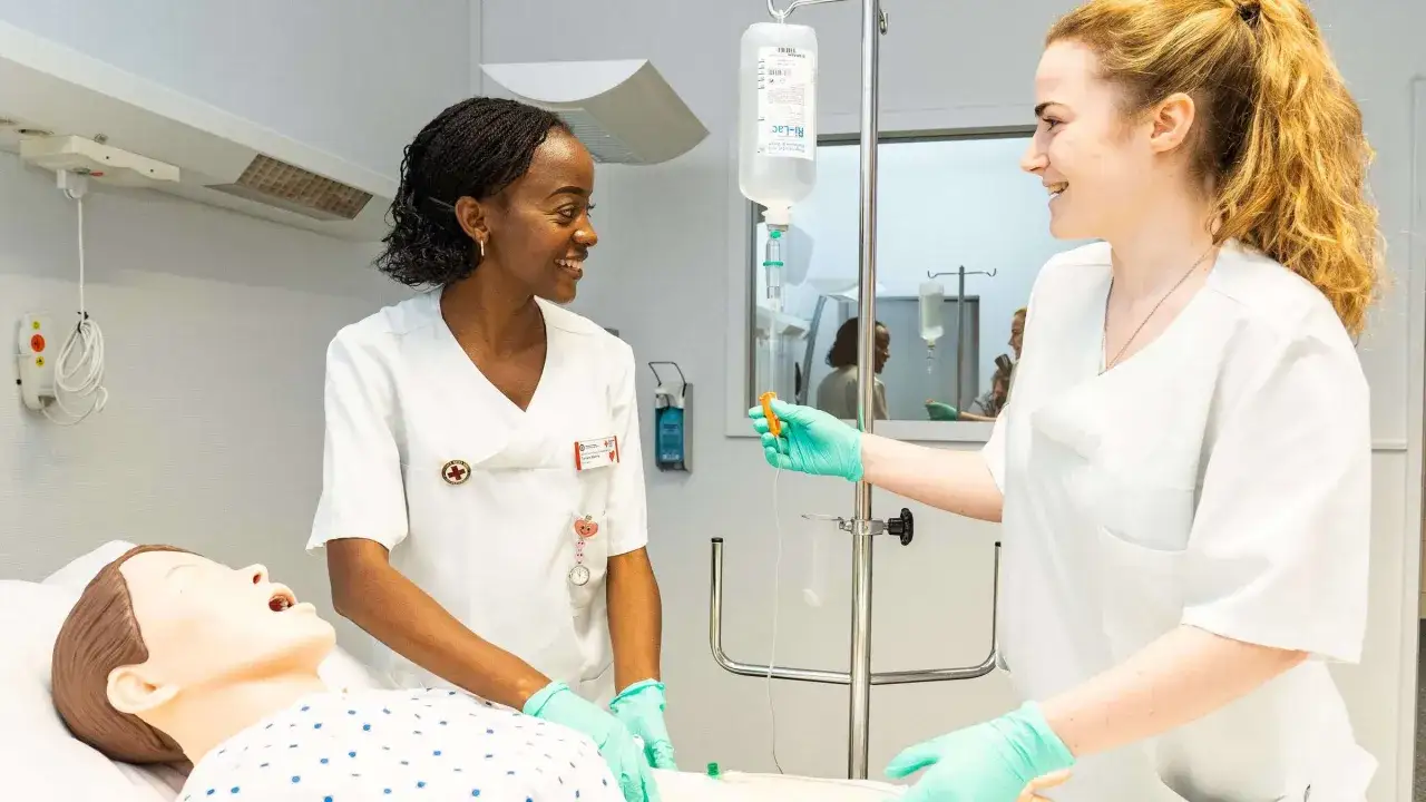 Zwei Pflegekräfte üben das Legen von Infusionen an einer Übungspuppe.