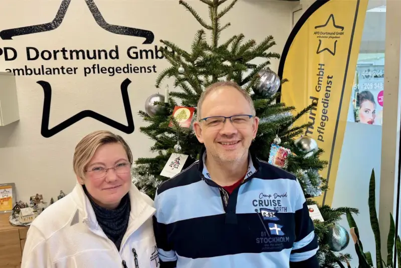 Zwei Mitarbeiter des ambulanten Pflegedienstes APD Dortmund stehen vor einem Weihnachtsbaum. Bei Fragen zum pflegedienst beschwerdestelle nrw sind sie gerne für Sie da.